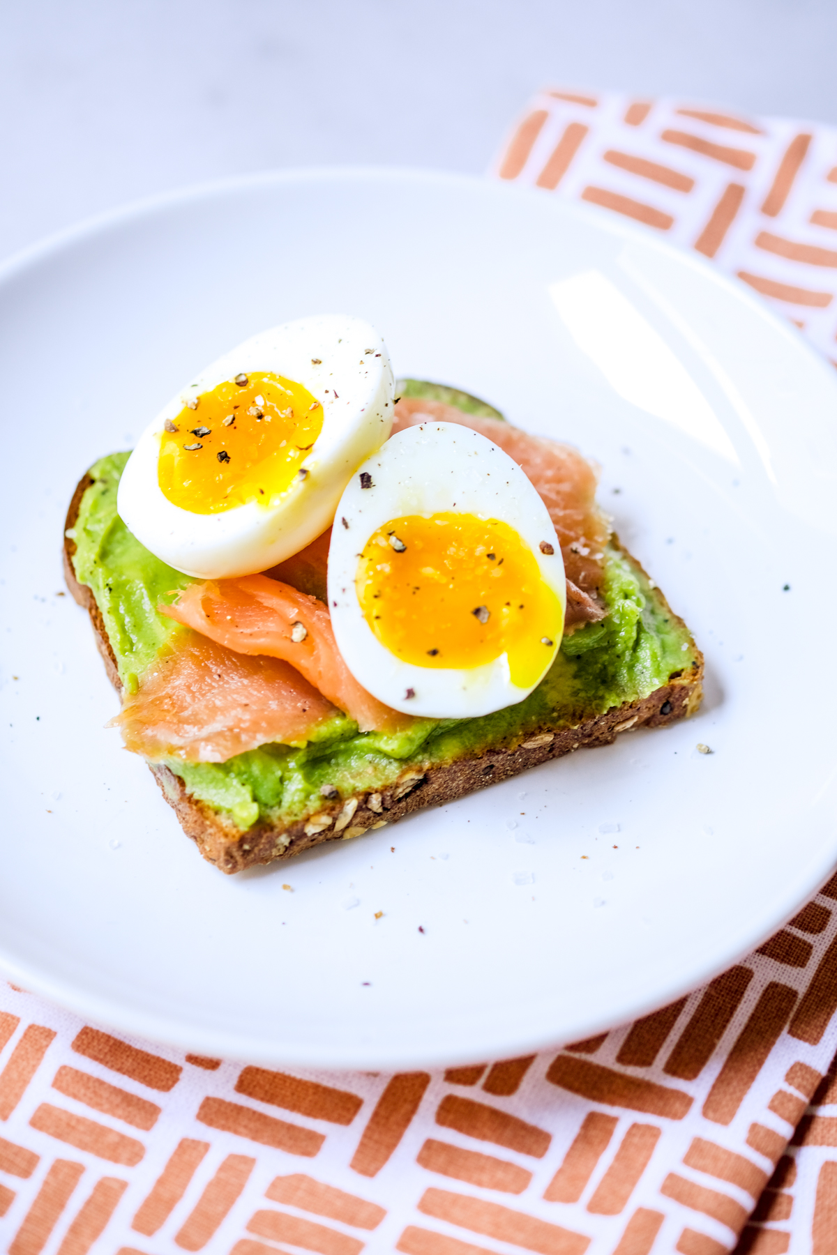 avocado toast with slices of smoked salmon and a soft boiled egg
