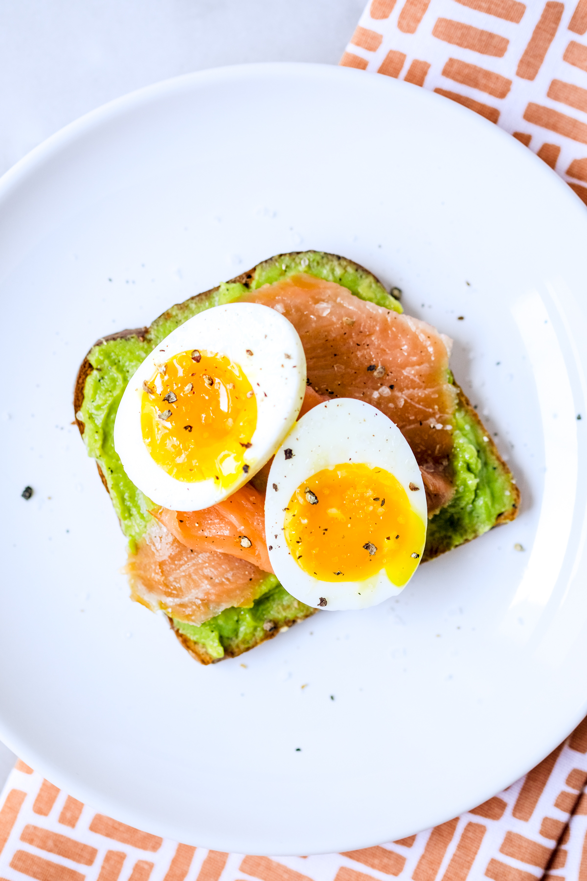 smoked salmon avocado toast with a soft boiled egg and fresh cracked pepper