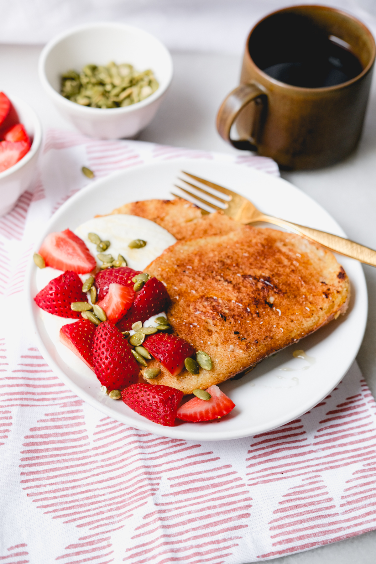 breakfast table with honey whipped ricotta french toast with strawberries and coffee in a mug