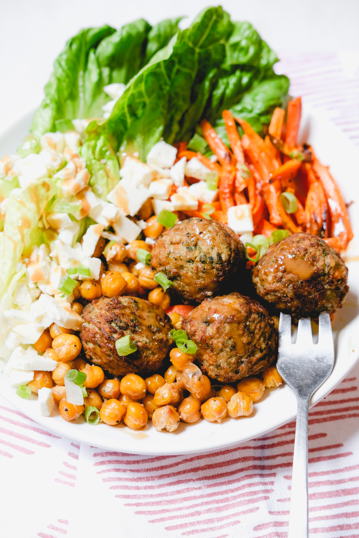 meatball and chickpeas in a salad with carrots, lettuce, and feta cheese