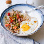 savory oatmeal in a bowl with eggs veggies and hot sauce