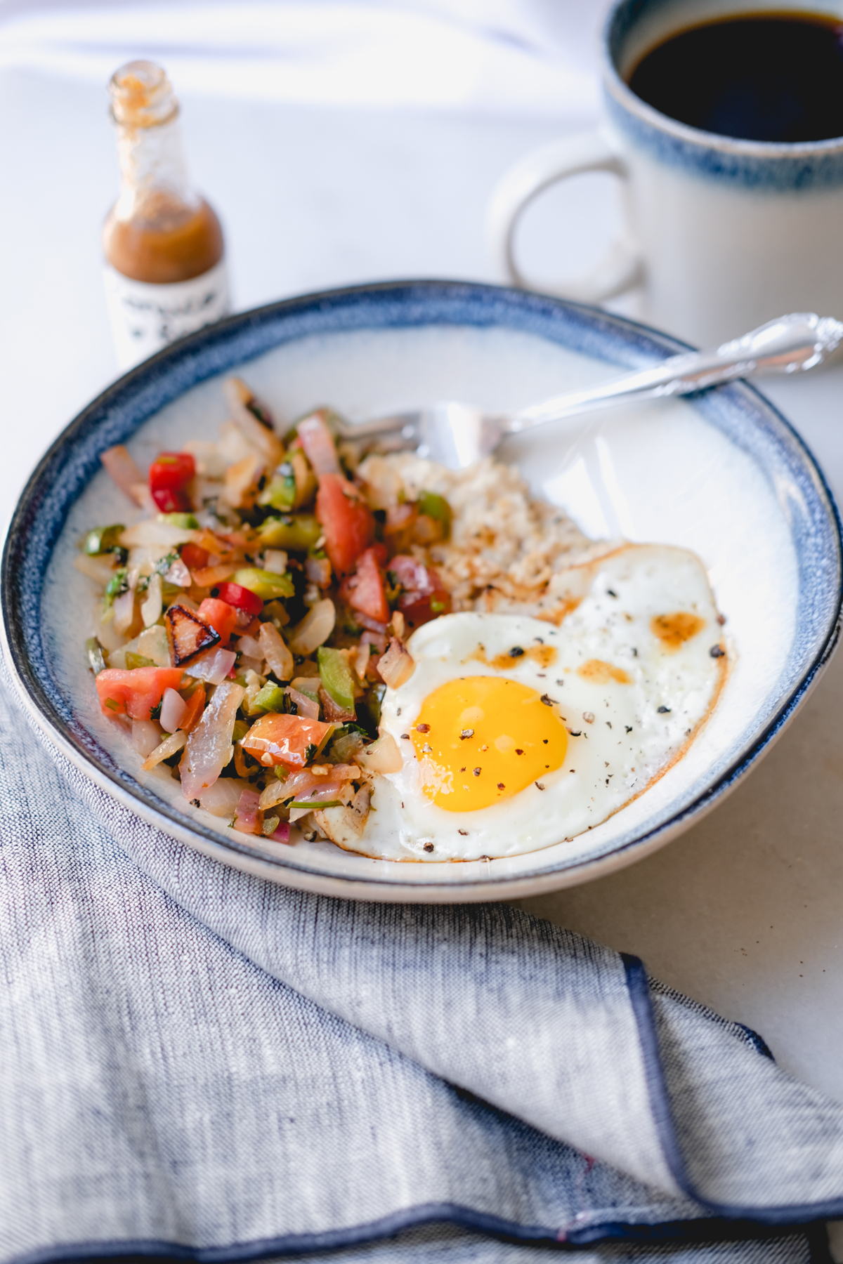 savory oatmeal in a bowl with eggs veggies and hot sauce