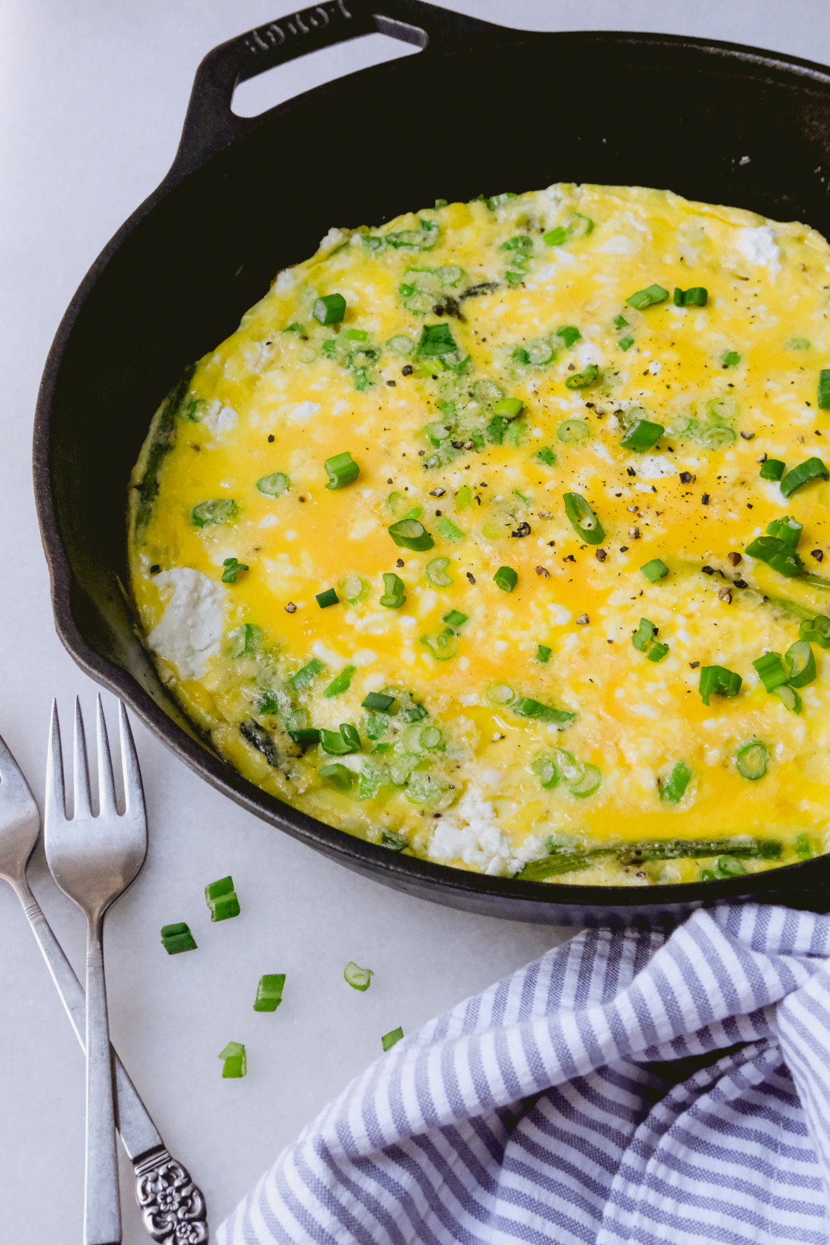 spring asparagus frittata in a cast iron skillet with green onions on top