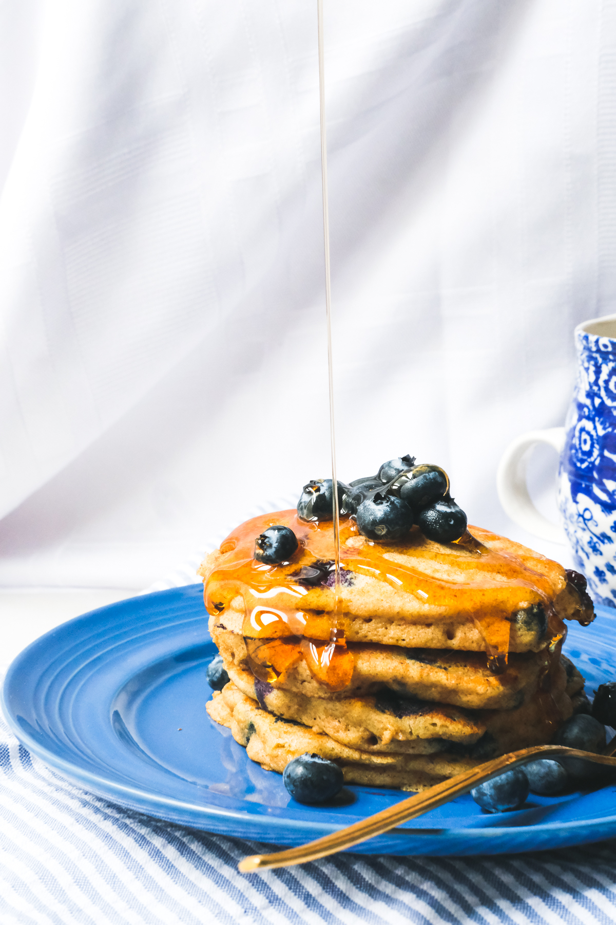stack of whole wheat blueberry pancakes with a syrup drizzle
